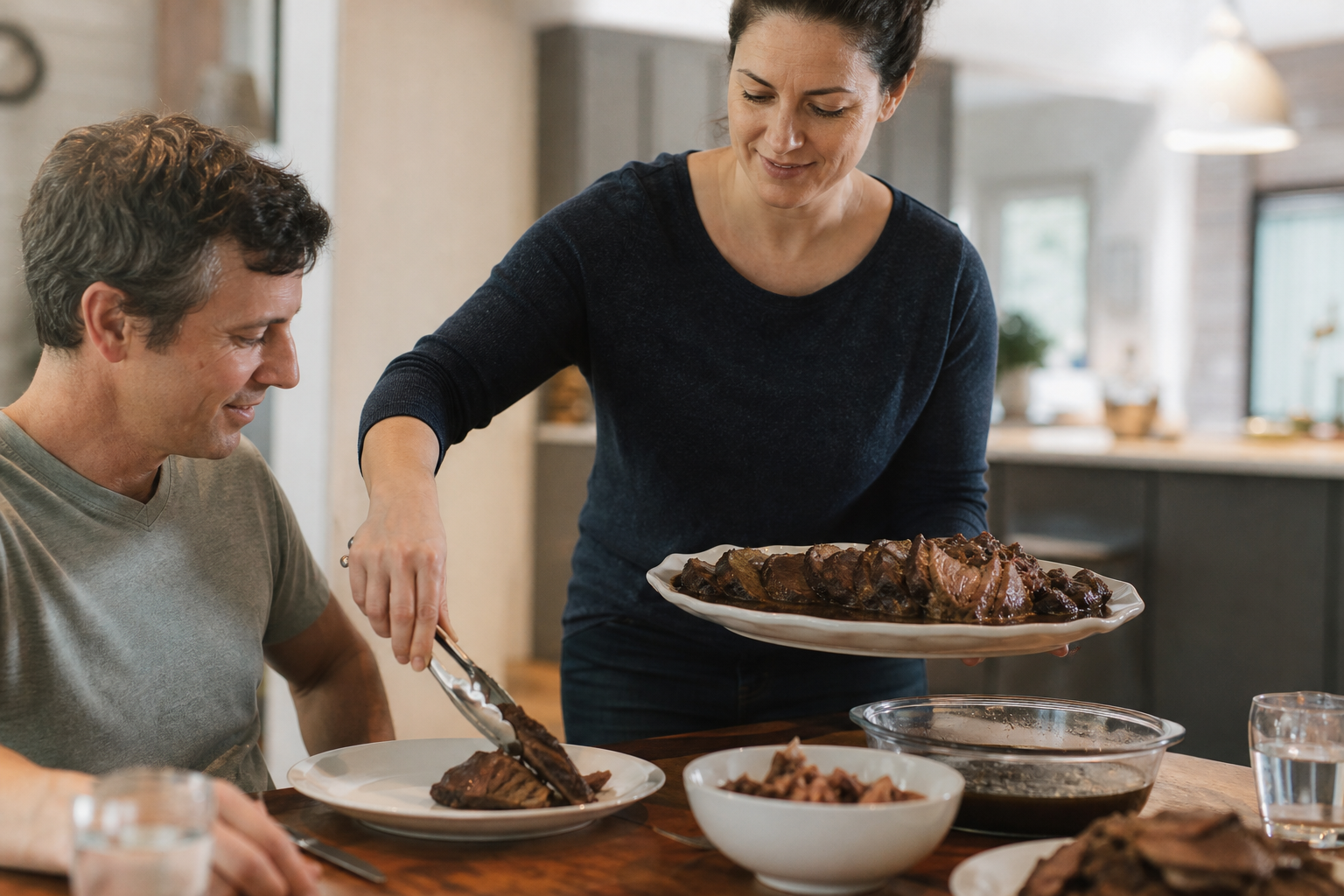 Woman serving sliced slow-braised chuck roast at a family dinner table.
